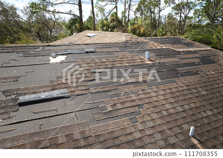 Damaged house roof with missing shingles after hurricane Ian in Florida. Consequences of natural disaster 111708355
