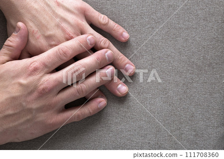 Close-up of male masculine young worker hands with rough skin and short fingernails resting on flat copy space background, top view. Manual labor and hands care concept. Close-up of male masculine young worker hands with rough skin and short fingernails resting on flat copy space background, top view. Manual labor and hands care concept. 111708360