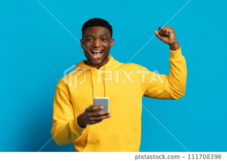Emotional funny black guy using smartphone gesturing with excitement Emotional funny black guy using smartphone gesturing with excitement 111708396