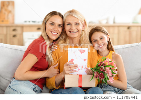 Grown daughter and teen granddaughter share loving hug with grandmother 111708441