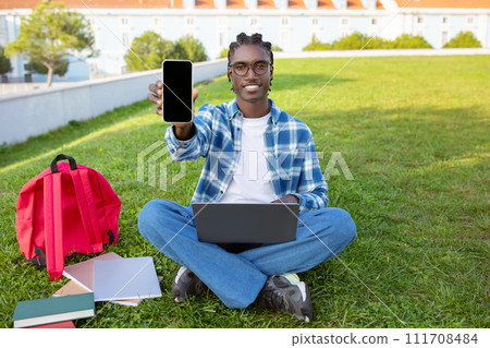 Happy African American guy shows blank screen on smartphone outdoors Happy African American guy shows blank screen on smartphone outdoors 111708484