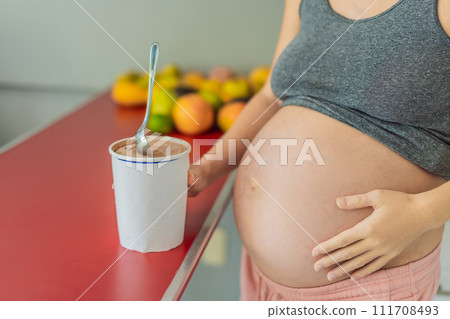Happy pregnant young woman eating ice cream 111708493