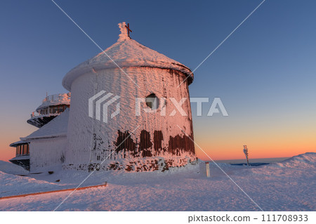 Winter, sunrise time, wooden Roman catholic chapel and disc shaped meteorological observatory in snezka, mountain on the border between Czech Republic and Poland. 111708933