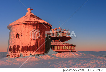 Winter, sunrise time, wooden Roman catholic chapel and disc shaped meteorological observatory in snezka, mountain on the border between Czech Republic and Poland. 111708935