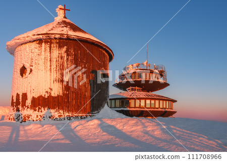 Winter, sunrise time, wooden Roman catholic chapel and disc shaped meteorological observatory in snezka, mountain on the border between Czech Republic and Poland. Winter, sunrise time, wooden Roman catholic chapel and disc shaped meteorological observatory in snezka, mountain on the border between Czech Republic and Poland. 111708966