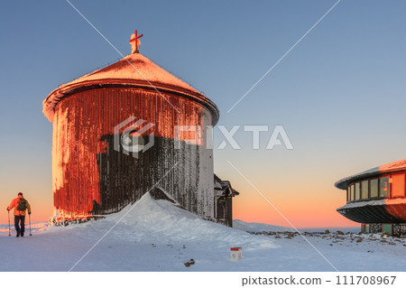 Winter, sunrise time, wooden Roman catholic chapel and disc shaped meteorological observatory in snezka, mountain on the border between Czech Republic and Poland. 111708967