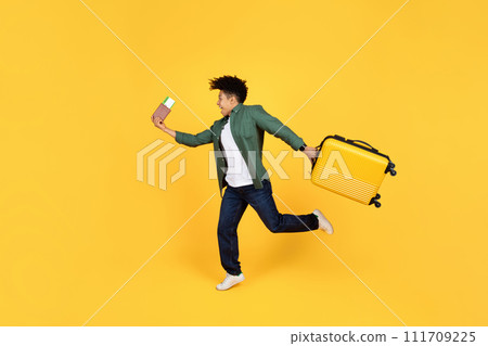 Excited young guy with luggage and passport running on yellow 111709225