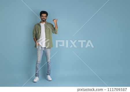 Cool millennial indian guy pointing at copy space Cool millennial indian guy pointing at copy space 111709387