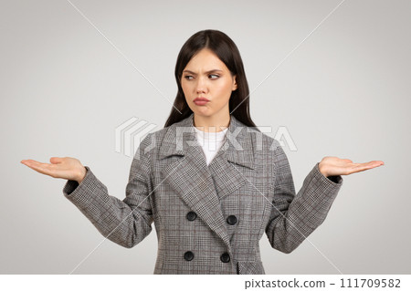 Perplexed young businesswoman with palms up in uncertainty Perplexed young businesswoman with palms up in uncertainty 111709582