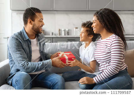 Portrait of little black son making surprise for father, giving present box Portrait of little black son making surprise for father, giving present box 111709587