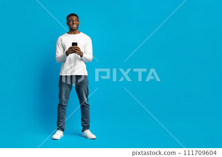Black Guy Holding Smartphone And Looking Aside At Copy Space Black Guy Holding Smartphone And Looking Aside At Copy Space 111709604