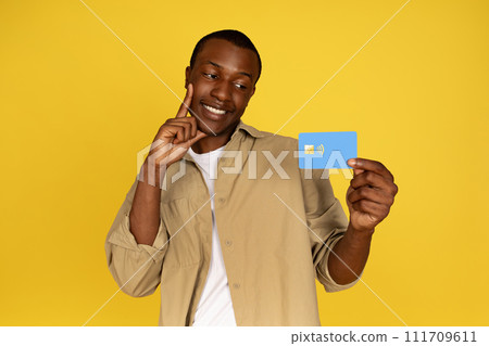 Glad young black man in casual look at credit card, enjoy shopping, pay money, profit, savings 111709611