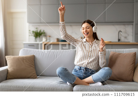 Joyful young woman dancing to music with headphones on 111709615