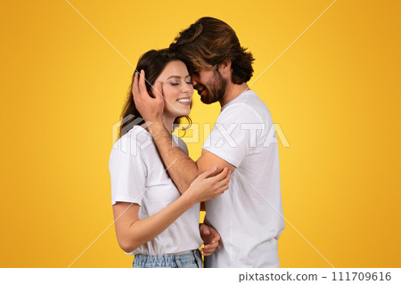 Intimate couple in white t-shirts share a tender moment, with the man gently cradling the woman's face 111709616