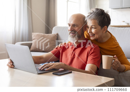Tech-Savvy Seniors. Happy Older Couple Using Laptop Together At Home Tech-Savvy Seniors. Happy Older Couple Using Laptop Together At Home 111709668