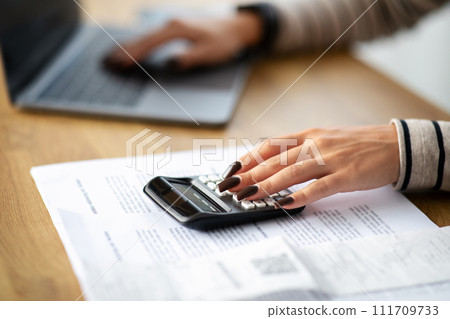 Young arab woman manager work at computer, calculator, pay bill taxes at table, cropped 111709733