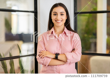Smiling young european businesswoman manager with crossed arms on chest 111709739