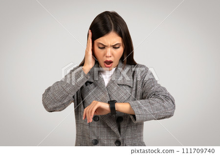 Stressed businesswoman checking time on smartwatch 111709740