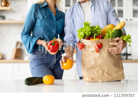 Unrecognizable Senior Couple Taking Out Fresh Vegetables Of Paper Groceries Bag Unrecognizable Senior Couple Taking Out Fresh Vegetables Of Paper Groceries Bag 111709787