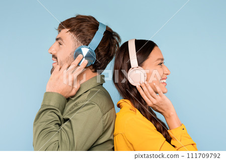 Happy man and woman in colorful clothes with headphones back to back, side view Happy man and woman in colorful clothes with headphones back to back, side view 111709792