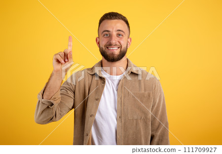 Happy young caucasian man with beard point finger up at free space 111709927