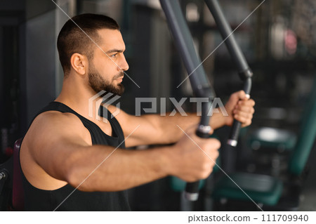 Portrait Of Motivated Muscular Man Training On Sport Machine At Gym Portrait Of Motivated Muscular Man Training On Sport Machine At Gym 111709940
