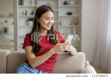 Mobile Banking. Asian Woman Using Smartphone While Sitting On Couch At Home 111709977