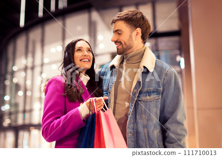 spouses embracing smiling with shopping bags outside of city mall 111710013