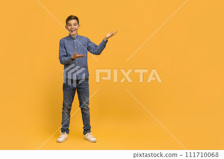 Cheerful teen boy in making presenting gesture with his hands 111710068