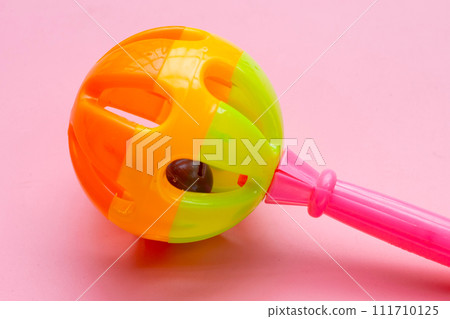 Colorful baby rattle on pink background. Copy space 111710125