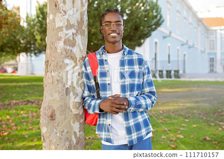 Confident African American young man student with backpack stands outdoor Confident African American young man student with backpack stands outdoor 111710157