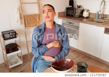 Pregnant woman in kitchen, feeling hunger and contemplating overeating Pregnant woman in kitchen, feeling hunger and contemplating overeating 111710167