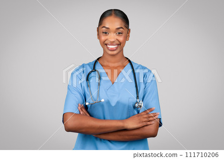 Smiling confident black millennial doctor surgeon, nurse in blue uniform with crossed arms on chest Smiling confident black millennial doctor surgeon, nurse in blue uniform with crossed arms on chest 111710206