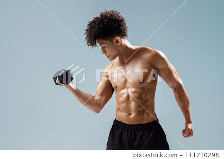 Athletic young man lifting dumbbells exercising over gray studio background Athletic young man lifting dumbbells exercising over gray studio background 111710298