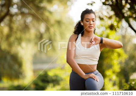 sportswoman doing aerobics outside, stretching legs in lunge monitoring watch sportswoman doing aerobics outside, stretching legs in lunge monitoring watch 111710610