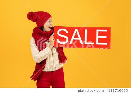 Lady holding poster board with word Sale on yellow background Lady holding poster board with word Sale on yellow background 111710633