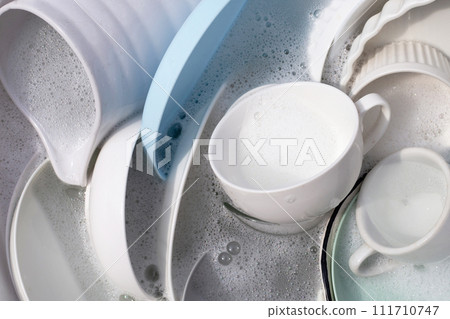 Dishes and bowls in water and bubbles of dishwashing liquid. Kitchen work 111710747