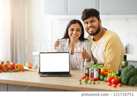 Beautiful loving spouses making food, watching video content on laptop Beautiful loving spouses making food, watching video content on laptop 111710751