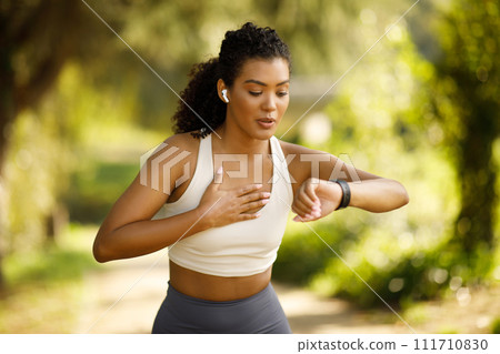 woman runner checking smartwatch pausing and breathing in run outdoors 111710830