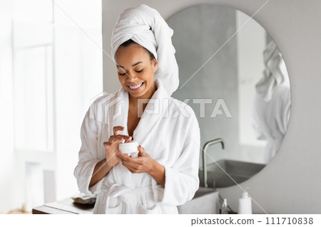 black young lady opens jar of cream moisturizer in bathroom 111710838
