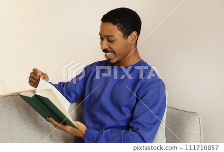 African American young man engrossed in literature, reading book indoor 111710857