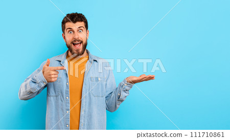 Excited guy points at his hand showing copy space, studio 111710861