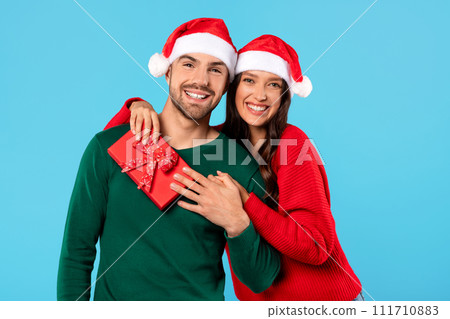 couple posing with Xmas gift box on blue studio background 111710883