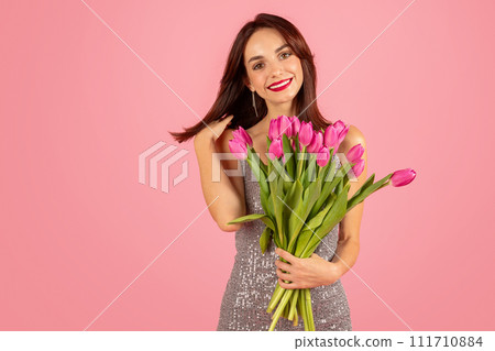 Gleeful young woman with lustrous hair, holding a lush bouquet of pink tulips Gleeful young woman with lustrous hair, holding a lush bouquet of pink tulips 111710884