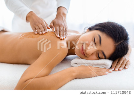 Woman enjoys exfoliating back scrub at spa Woman enjoys exfoliating back scrub at spa 111710948