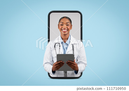 Positive young black lady doctor therapist in white coat typing on tablet, on big phone screen 111710950