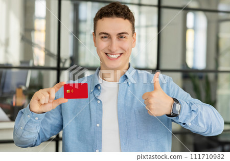 Happy handsome millennial caucasian guy manager show credit card and thumb up Happy handsome millennial caucasian guy manager show credit card and thumb up 111710982