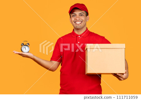 Cheerful courier guy holding parcel carton box and clock, studio 111711059