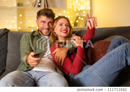Couple cuddling and watching TV at home 111711082