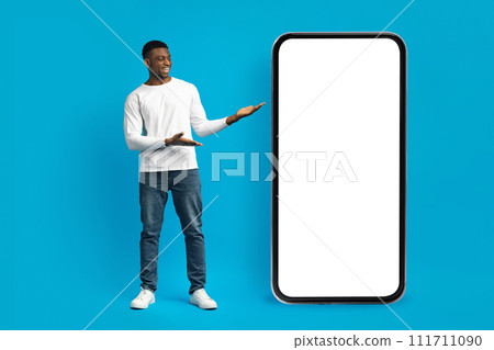 Stylish millennial african american guy posing by huge smartphone 111711090